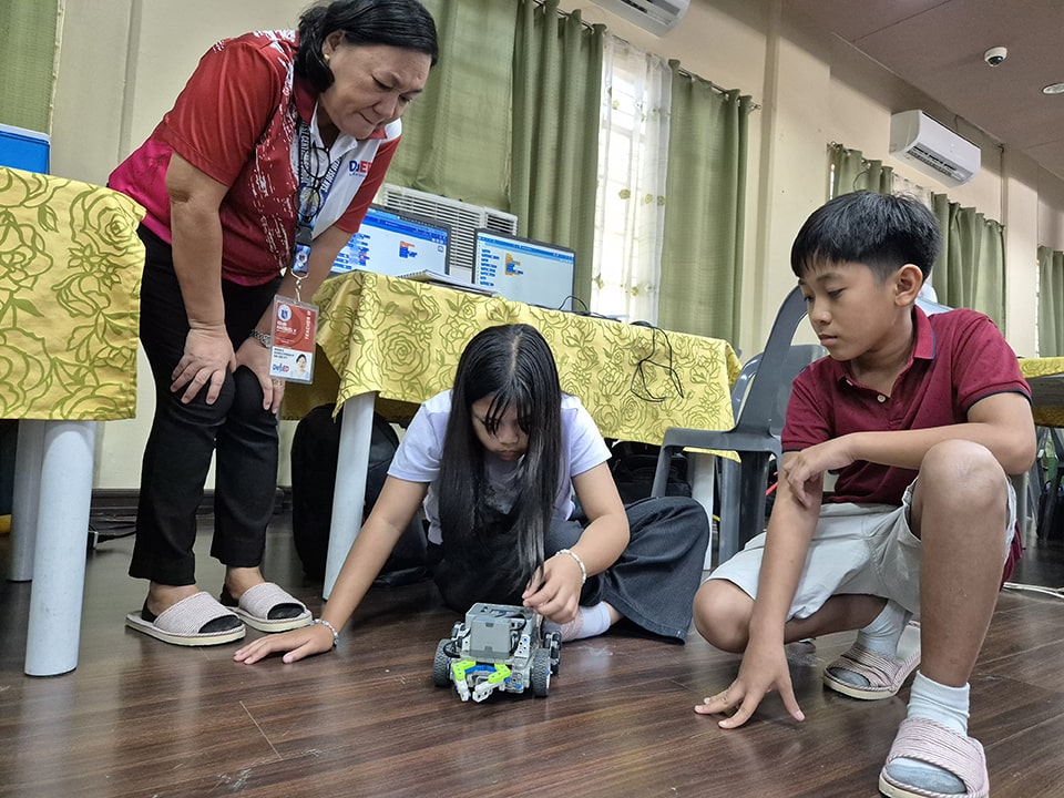 Training instructors from San Jose oversee students' coded agri-robot.